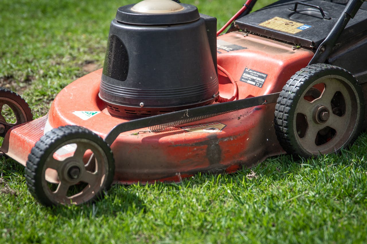 A close-up view of a red lawn mower on a green lawn, showcasing its details.